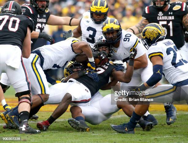 Running back Ty'Son Williams of the South Carolina Gamecocks is stopped by defensive back Khaleke Hudson of the Michigan Wolverines and defensive...