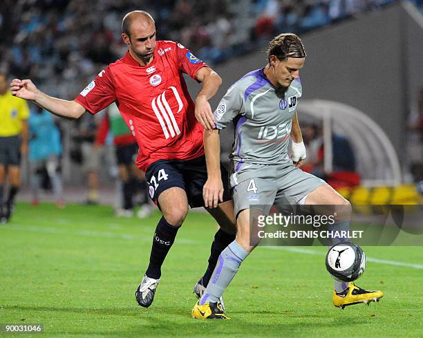 Lille's Slovakian forward Robert Vittek vies with Toulouse defender Mauro Cetto during the French L1 football match Lille vs. Toulouse on August 23,...