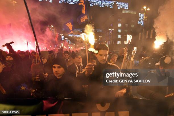 People hold torches during a march in Kiev on January 1, 2018 to mark the 109th anniversary of the birth of Ukrainian politician Stepan Bandera, one...