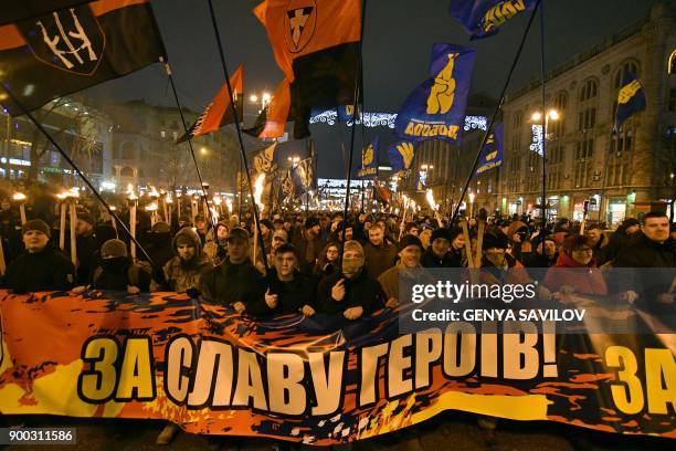 People hold torches and a banner during a march in Kiev on January 1, 2018 to mark the 109th anniversary of the birth of Ukrainian politician Stepan...
