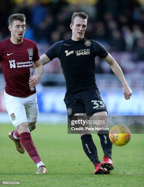 Dan Burn of Wigan Athletic plays the ball under pressure from Chris Long of Northampton Town during the Sky Bet League One match between Northampton...