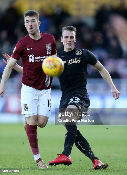 Dan Burn of Wigan Athletic plays the ball under pressure from Chris Long of Northampton Town during the Sky Bet League One match between Northampton...