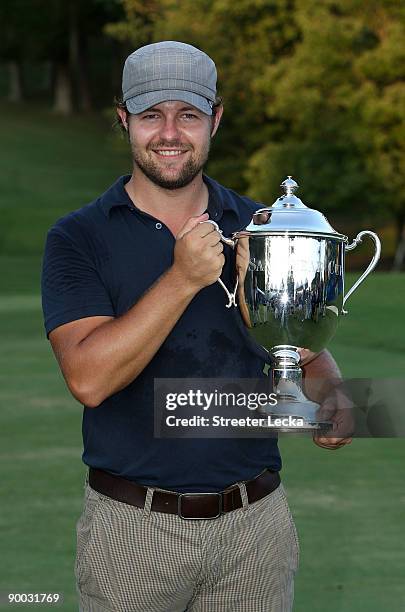 Ryan Moore poses with the winner's trophy after winning the Wyndham Championship in a sudden death playoff against Kevin Stadler and Jason Bohn at...