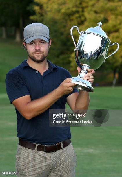 Ryan Moore poses with the winner's trophy after winning the Wyndham Championship in a sudden death playoff against Kevin Stadler and Jason Bohn at...