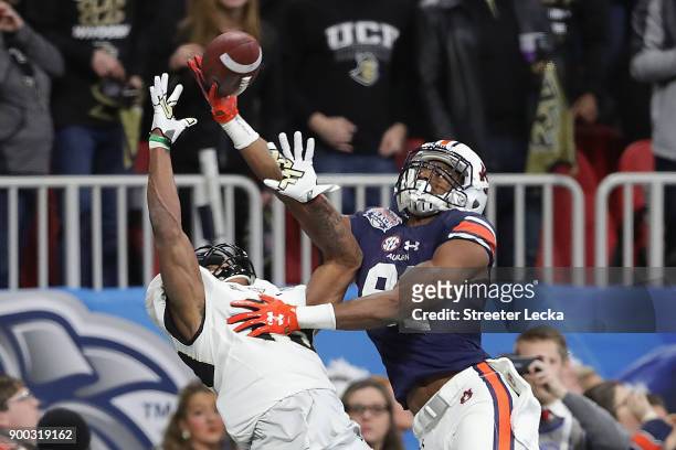 Mike Hughes of the UCF Knights and Darius Slayton of the Auburn Tigers battle for the ball in the first half during the Chick-fil-A Peach Bowl at...