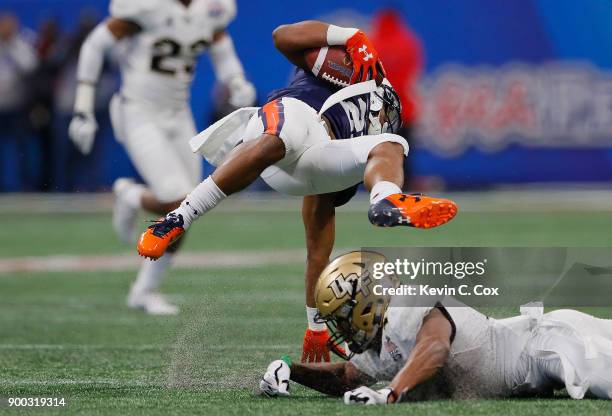 Ryan Davis of the Auburn Tigers is tackled by Mike Hughes of the UCF Knights in the first half during the Chick-fil-A Peach Bowl at Mercedes-Benz...