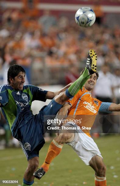 Brian Mullan of the Houston Dynamo avoids being kicked from Leo Gonzalez of the Seattle Sounders FC at Robertson Stadium on August 23, 2009 in...