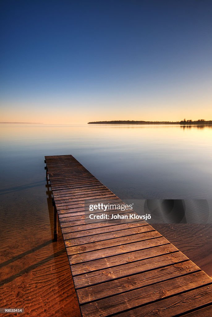 Pontoon on a still lake in sunset