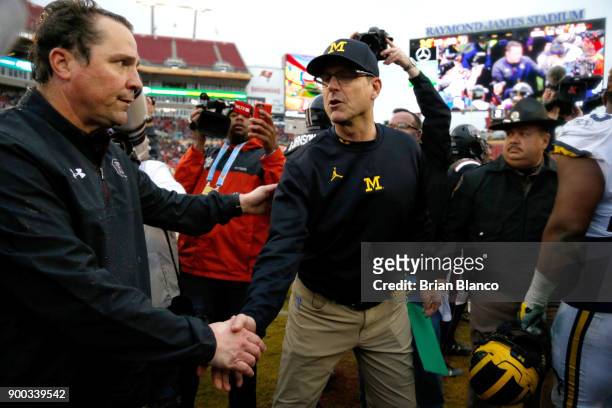 Head coach Will Muschamp of the South Carolina Gamecocks shakes hands on the field with head coach Jim Harbaugh of the Michigan Wolverines following...