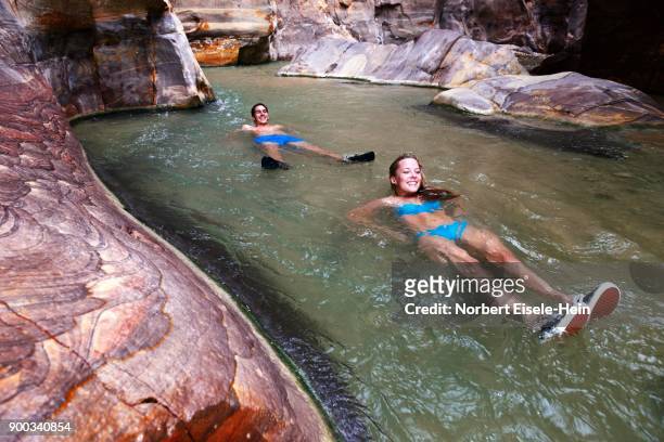 young couple floats at the canyon of wadi mujib, jordan - canyoneering stock pictures, royalty-free photos & images