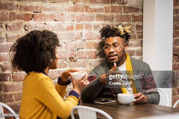 young mixed race couple talking in coffee shop - coffee shop couple stock pictures, royalty-free photos & images