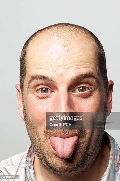 bald man sticking out his tongue - bald man foto e immagini stock