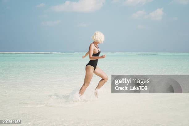 active woman running through ocean, maldives - beach vibes stock pictures, royalty-free photos & images