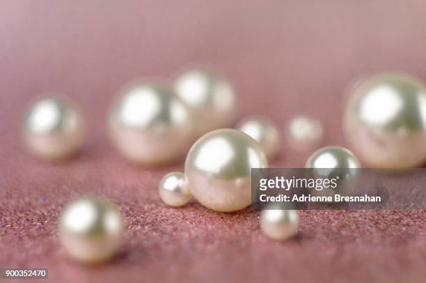 loose white pearls on pink background - perle foto e immagini stock