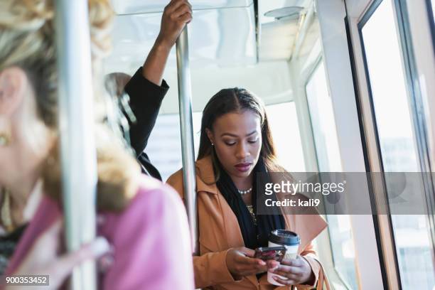 afro-amerikanische frau reiten zug, sms - winter woman phone stock-fotos und bilder