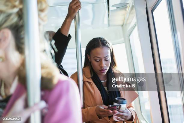 tren de conducción mujer afroestadounidense, mensajes de texto - busy train fotografías e imágenes de stock