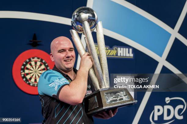 English professional darts player, Rob Cross holds aloft the winner's trophy after beating English professional darts player, Phil Taylor during the...