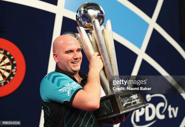 Rob Cross of England poses with the Sid Waddell Trophy after winning the PDC World Darts Championship final against Phil Taylor of England on Day...