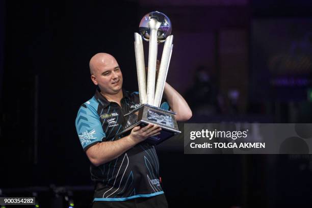 English professional darts player, Rob Cross holds aloft the winner's trophy after beating English professional darts player, Phil Taylor during the...