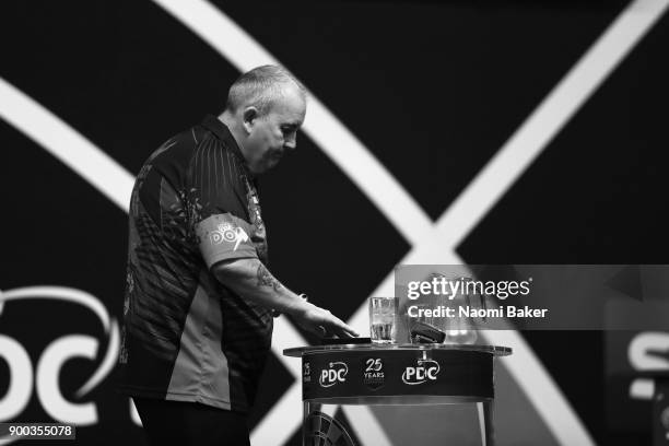 Phil Taylor of England collects his darts during the PDC World Darts Championship final against Rob Cross of England on Day Fifteen at the 2018...