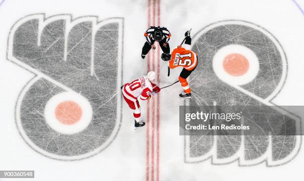 Referee Kelly Sutherland prepares to drop the puck on a face-off between Valtteri Filppula of the Philadelphia Flyers and Henrik Zetterberg of the...
