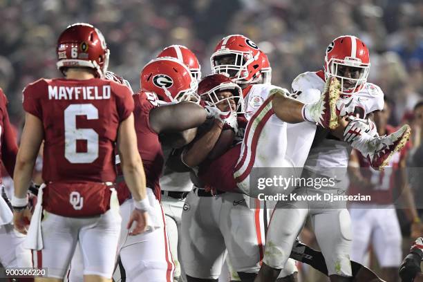 Running back Rodney Anderson of the Oklahoma Sooners is picked up as he tries to run against the Georgia Bulldogs defense in the second half in the...