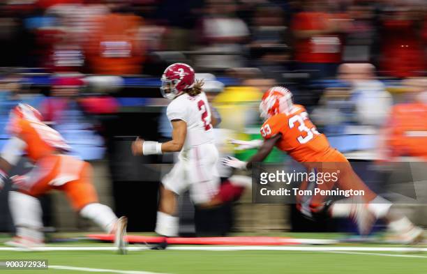 Jalen Hurts of the Alabama Crimson Tide runs with the ball as J.D. Davis of the Clemson Tigers defends in the first half of the AllState Sugar Bowl...