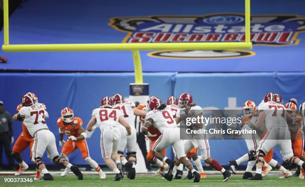 Jalen Hurts of the Alabama Crimson Tide hands the ball to Bo Scarbrough in the first half of the AllState Sugar Bowl against the Clemson Tigers at...