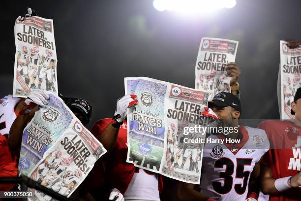 The Georgia Bulldogs celebrate with newspapers after the Bulldogs beat the Oklahoma Sooners 54-48 in double overtime in the 2018 College Football...