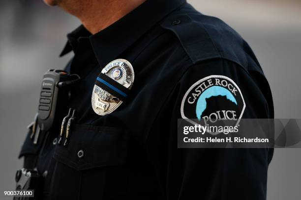 Castle Rock police officer, wearing black over his badge, arrives for a candlelight vigil for slain Douglas County deputy sheriff Zackari Parrish at...