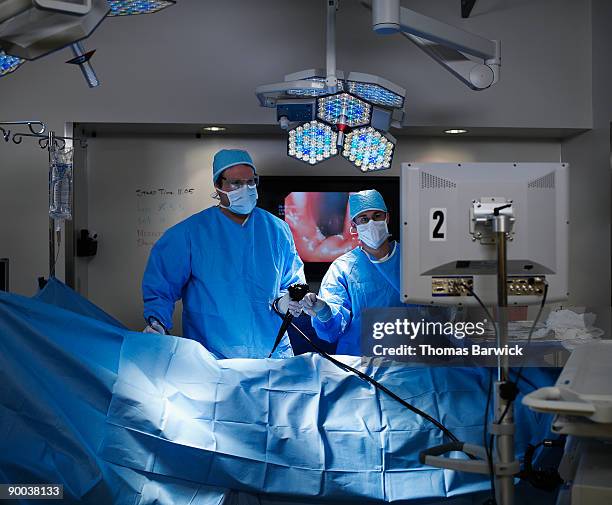 surgeon and assistant preforming endoscopy - endoscopio fotografías e imágenes de stock