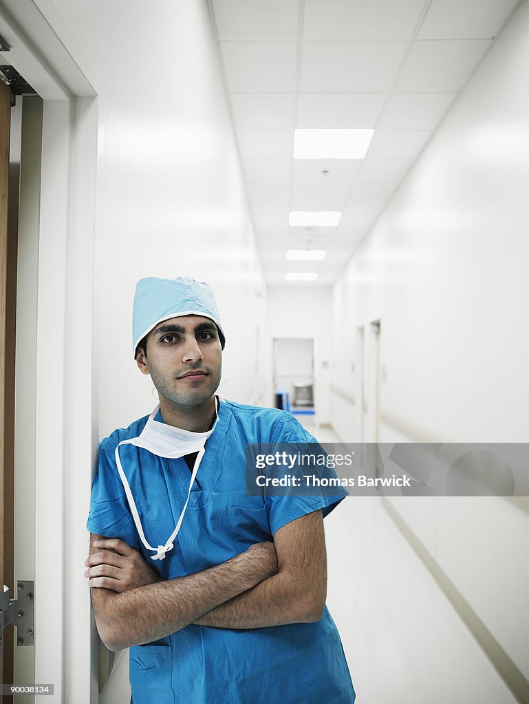 Surgeon leaning against doorway in hallway