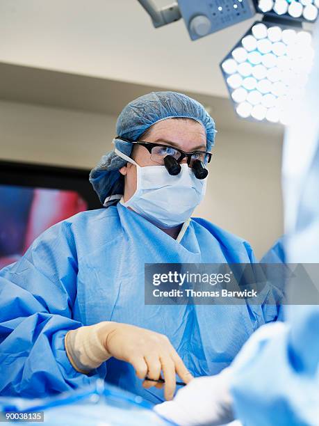 female surgeon looking up during surgery - surgical loupes stock pictures, royalty-free photos & images