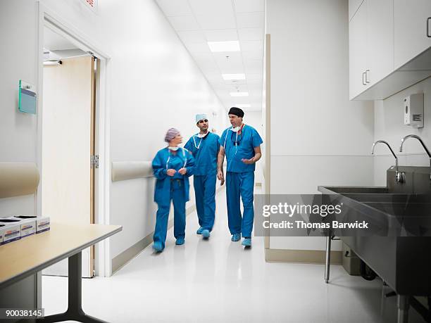 surgeons walking in hospital hallway - surgeon walking stock pictures, royalty-free photos & images
