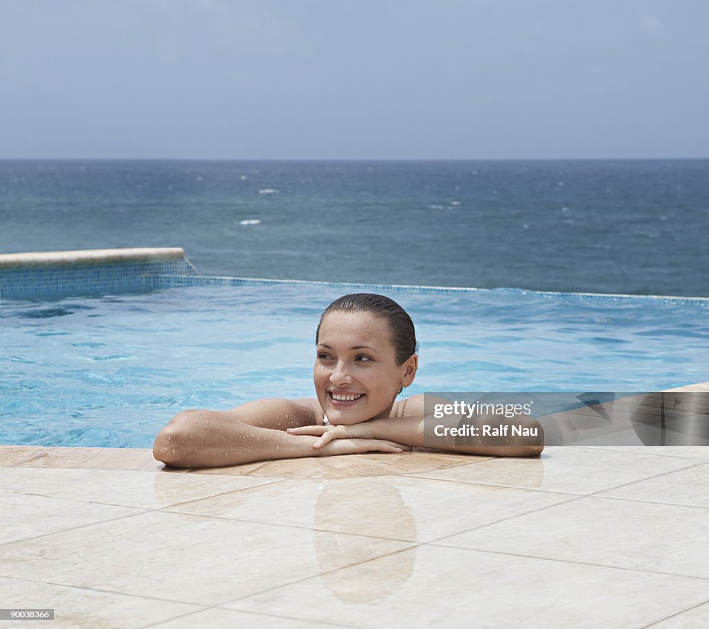 Woman in infinity pool resting on edge