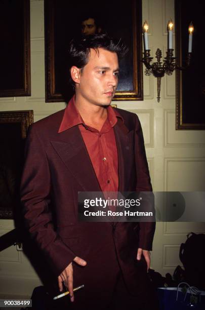 Portrait of American actor Johnny Depp, a cigarette and holder in hand, as he poses in the Great Hall at The Players social club during a reception,...
