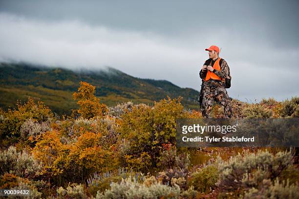hunter with binoculars and rifle looking out.  - pic hunter imagens e fotografias de stock
