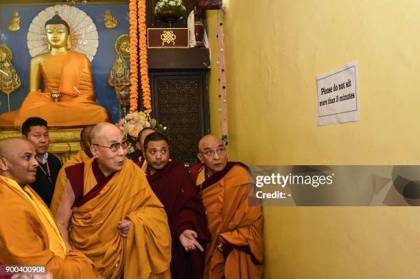 Tibetan spiritual leader the Dalai Lama and his entourage look at a sign warning against sitting too long at Mahabodhi Temple during his visit to...