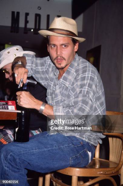American actor Johnny Depp uncorks a bottle of wine on a podium in the atrium of the Times Square Virgin Megastore, New York, New York, May 21, 1998....
