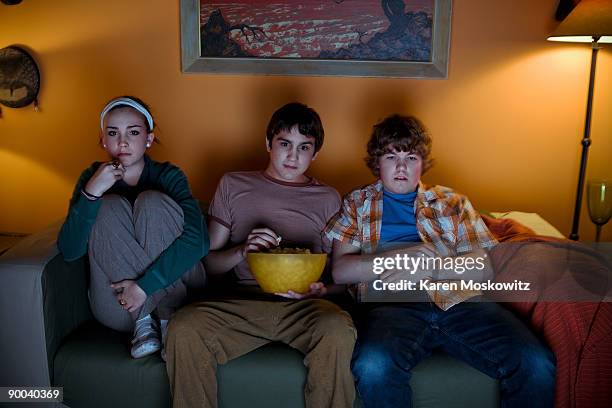 teens watching tv - three people on couch stock pictures, royalty-free photos & images