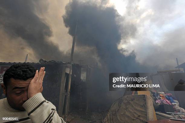 Resident protects himself from the smoke coming out of a fire during an eviction at Capao Redondo shantytown, southern outskirts of Sao Paulo,...