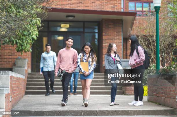 two ethnic college friends leave class together and walk across campus. - walking away from camera stock pictures, royalty-free photos & images