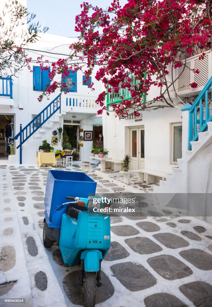 Narrow Street in Mykonos Town with Blue Motorbike and Bougainvillea Flowers