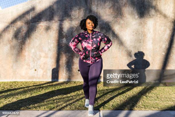 curvilínea jovem negra exercendo, tendo formação de desporto no parque público da cidade - curvy black women - fotografias e filmes do acervo