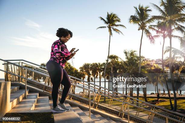 bochtige jonge zwarte vrouw uit te oefenen, met sport opleiding in miami beach openbaar park - palm tree stockfoto's en -beelden