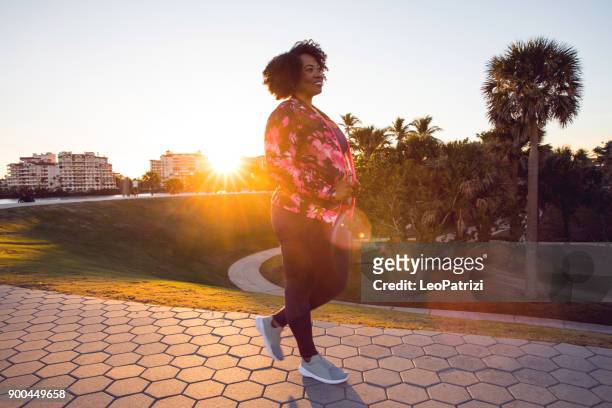 Curvy young black woman walking, jogging and running in the city public park