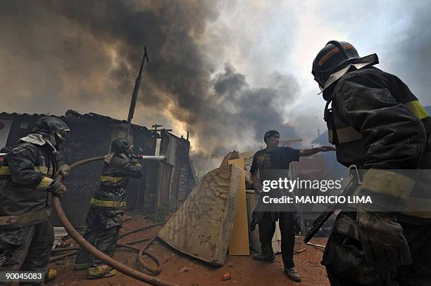 Resident refuses to leave as firefighters extinguish a fire amid a dense plume of smoke during an eviction at Capao Redondo shantytown, southern...