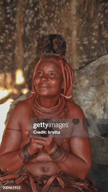 verheiratete himba frau sitzt im inneren der hütte im dorf in der nähe von opuwo - opuwo tribe stock-fotos und bilder