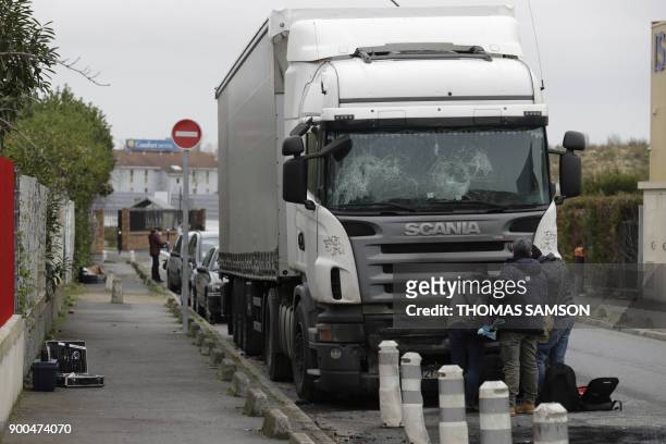 Police investigators look for evidence around a damaged truck which windshield was smashed, on January 2, 2018 in the Paris suburb of...