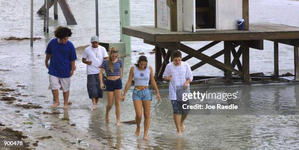 Group of teenagers wade through water left by Hurricane Michelle which skirted the South Florida coast on the walkway along the beach November 5 in...